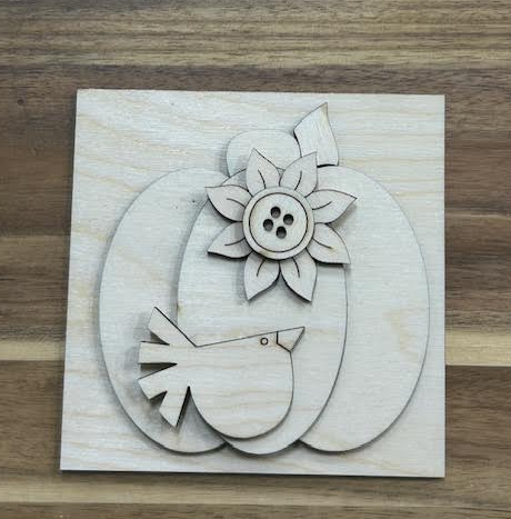 Unfinished pumpkin frame insert with a little bird and layered flower with a button-style center