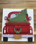 Hand-painted red Christmas truck frame insert with a green tree, wreath, red bow and U-CUT license plate