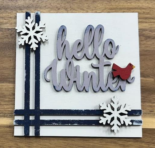 Finished Hello Winter frame insert with gray lettering, a red bird, white snowflakes, and dark stripes on a white background