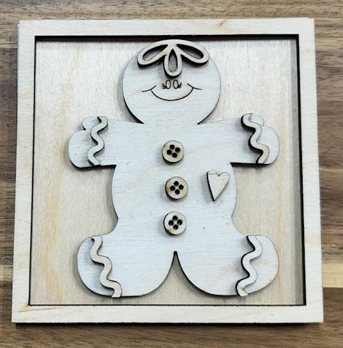 Unfinished gingerbread man wood insert with bow, buttons, heart, and icing details shown in a square frame