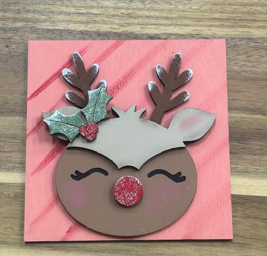 Hand-painted reindeer frame insert with a glittery red nose, holly, and brown antlers on a pink background