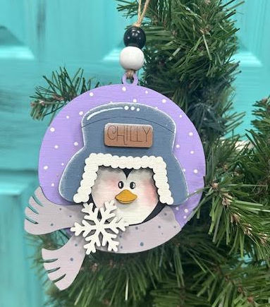 Hand-painted Chilly Penguin ornament with purple background, gray winter hat and scarf, white snowflake, and beaded hanger.