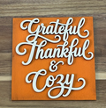 Finished orange frame insert with cream-colored Grateful Thankful & Cozy lettering