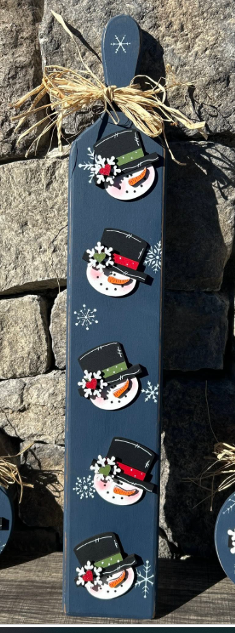 Tall country blue decorative bread board with five attached birch snowman heads and raffia bow