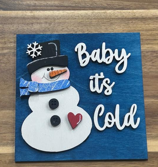 Baby It's Cold frame insert with a snowman wearing a black top hat and blue scarf, white lettering, and a red heart on a blue background
