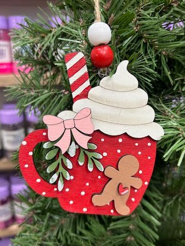 Hand-painted red hot cocoa mug wood ornament with gingerbread figure, pink bow, greenery, whipped cream, striped straw, and red and white beaded hanger