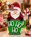 Finished Santa shelf sitter in a green Ho Ho Ho mug with red dots, holly, and a red-and-white candy cane