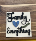Finished Family Is Everything frame insert with black script, a blue heart, and a green leafy sprig on a light background.