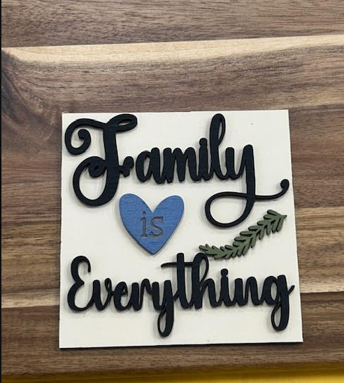 Finished Family Is Everything frame insert with black script, a blue heart, and a green leafy sprig on a light background.