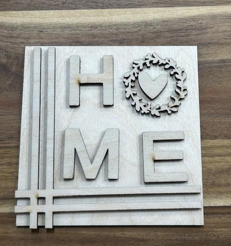 Unfinished HOME birch frame insert with a heart-centered leafy wreath replacing the O and line accents along the left and bottom.