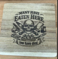 Square 8 x 8 inch acacia wood trivet engraved with Many Have Eaten Here, Few Have Died