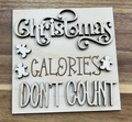Unfinished square wood insert reading Christmas Calories Don't Count with decorative lettering and gingerbread figures