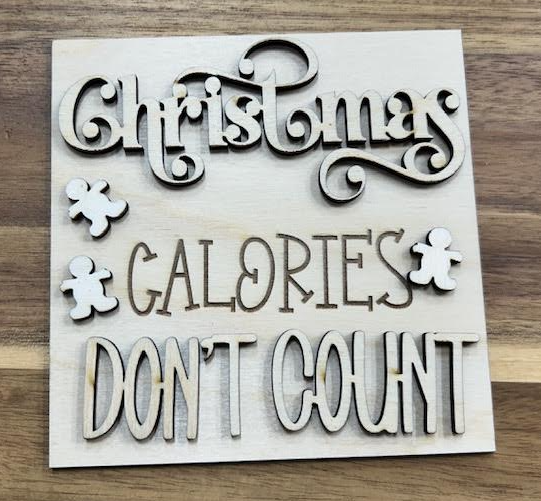 Unfinished square wood insert reading Christmas Calories Don't Count with decorative lettering and gingerbread figures