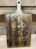 Wide-eyed chicken and She's Got a Knife saying laser engraved on a large acacia wood paddle charcuterie board