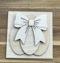Unfinished wood pumpkin with a large layered bow on a square frame insert